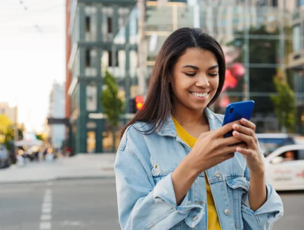 Mulher consultando o celular na rua